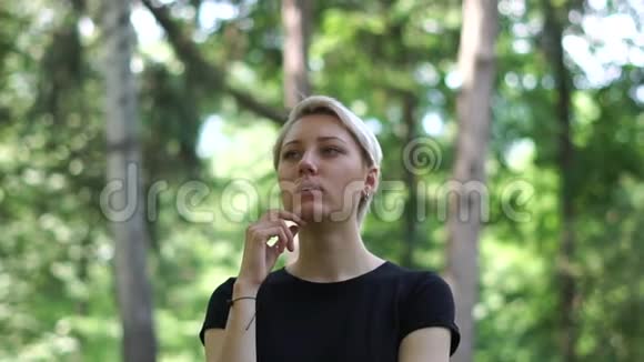 高贵的金发女人站着想着自己的生活在一片松松的森林里视频的预览图
