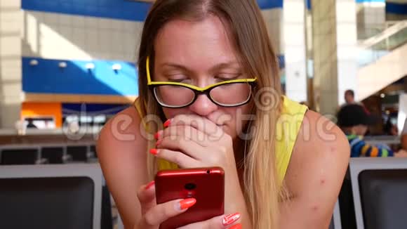 女人在机场浏览红色智能手机视频的预览图