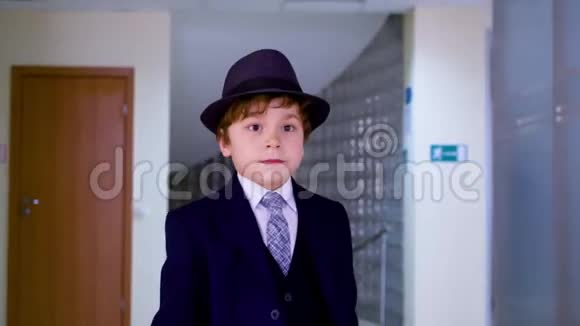 年轻的商人在商务办公室的走廊上散步穿着西装戴着帽子在学校走路的严肃的小男孩视频的预览图