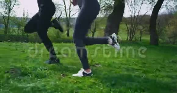 细节特写在大自然中两个跑步的女士一边拍着腿的视频一边穿过草地旁边的草地视频的预览图