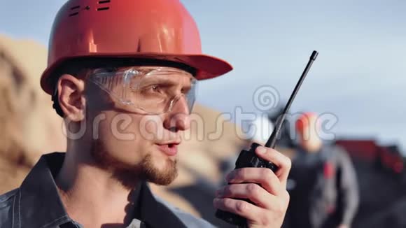 熟练的男性建筑工程师在工作特写时使用对讲机进行报道视频的预览图