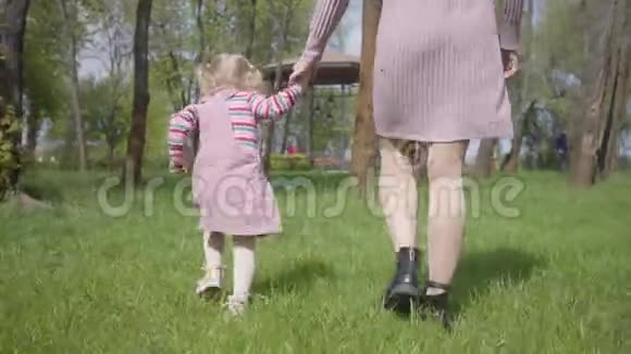 可爱的母亲和可爱的小女儿牵着手在惊人的绿色公园里跑来跑去女人和小孩玩视频的预览图