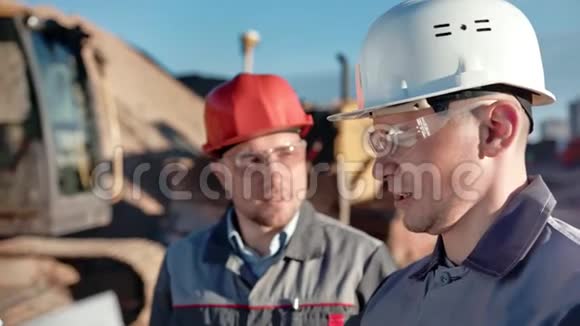 特写两名戴头盔和眼镜的男建筑工程师讨论工作视频的预览图