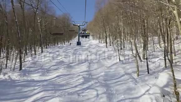 从滑雪斜坡的椅子升降台上可以看到覆盖着雪的树木视频的预览图