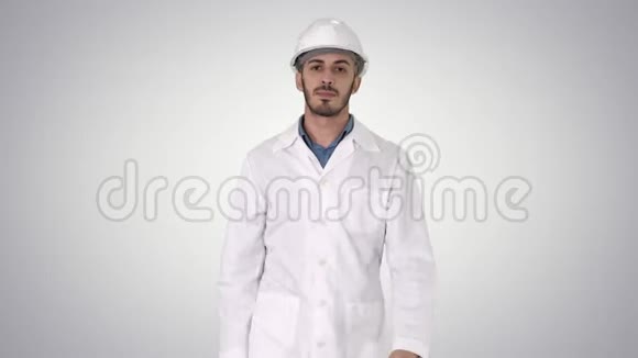 戴着头盔和白色长袍的阿拉伯工程师在梯度背景下向前走视频的预览图