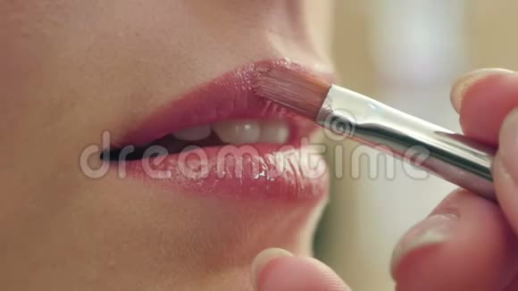 化妆师描绘了一个美丽的微笑女孩的嘴唇视频的预览图