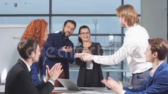 商务人士在面试时握手而其他人则在办公室拍手视频的预览图