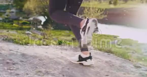一位身材健美的女士在山路上奔跑在令人惊叹的河景旁边奔跑双腿的细节视频的预览图