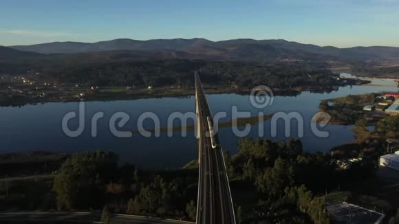 火车穿过大桥在日落时分从无人驾驶飞机上俯瞰河面视频的预览图