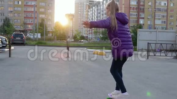 傍晚时分少女在城市街道的长板上滑滑板街上骑滑板的小女孩视频的预览图