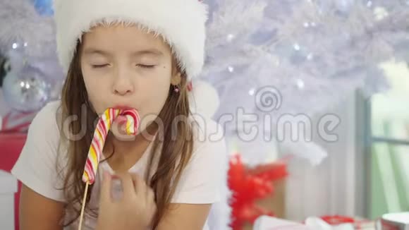 圣诞节早晨漂亮的小女孩正在品尝一种糖果看上去很好奇视频的预览图