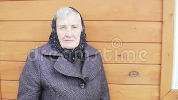 一位戴着黑色头巾的老奶奶正站在一所房子前视频的预览图