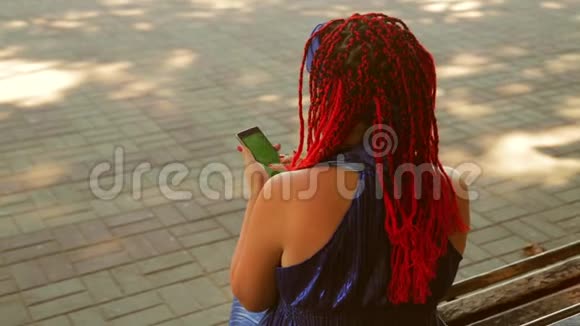 一位坐在公园长椅上的年轻女子在信使中交流视频的预览图