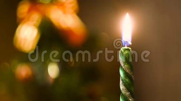 在模糊的彩色圣诞背景上点燃蜡烛概念关上绿色新年蜡烛的火焰视频的预览图