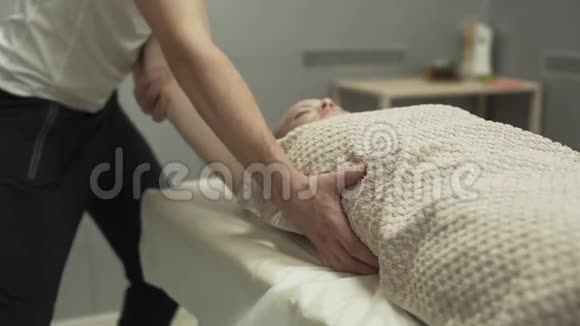 职业男性手按摩床上年轻女性的肩膀按摩治疗师的女孩视频的预览图