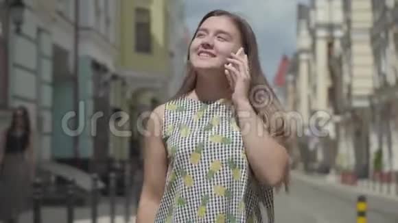 可爱的年轻女子在欧洲老城走来走去打电话挥动手臂快乐女孩的休闲视频的预览图