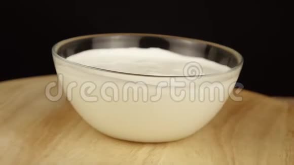 透明盘子里的酸奶油在黑色背景下旋转360度视频的预览图