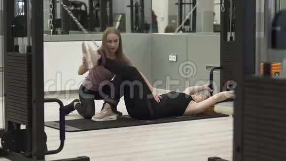 运动红发妇女与一名私人教练在健身房工作运动康复健康视频的预览图