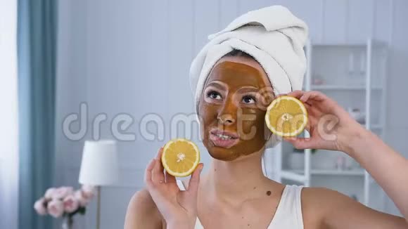 迷人的白种人女人摆着两半柠檬脸上戴着棕色面具视频的预览图