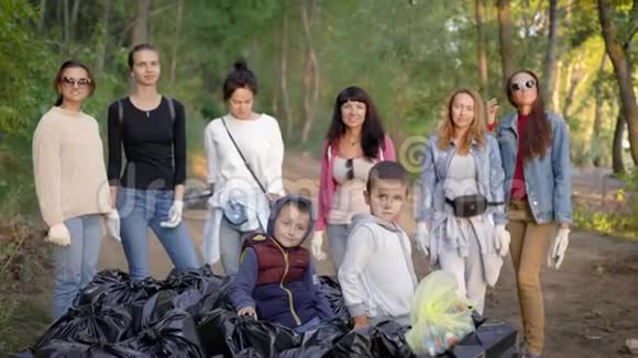 一群年轻的妇女和孩子们在大自然中收集了很多垃圾袋志愿者们对结果很满意视频的预览图