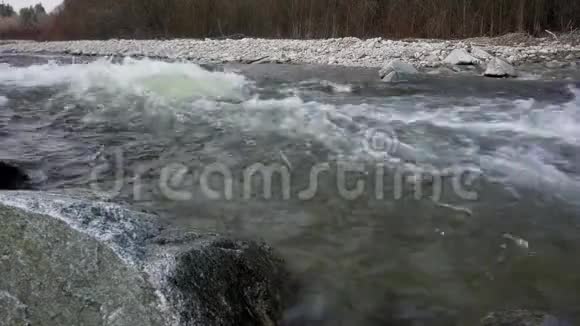 在阳光明媚的春天里河流水流上的白色波浪特写视频的预览图