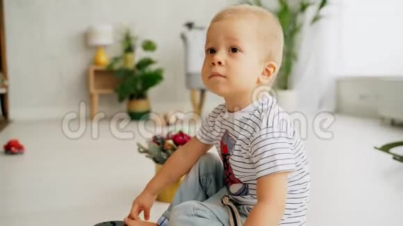 一个悲伤的小男孩坐在地板上肖像儿童看相机视频的预览图