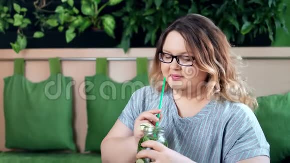 节食快乐的胖女人喝夏季健康鸡尾酒的肖像用草药看镜头视频的预览图