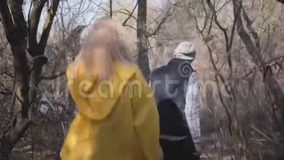 在灰色森林里散步的夫妇戴帽子戴太阳眼镜穿背心的人穿黄色外套的女人视频的预览图