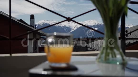乡村美丽山景的选择性聚焦桌上的橙汁杯在前面视频的预览图
