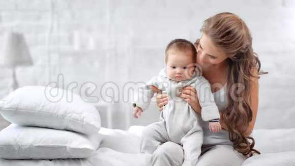 有爱心的年轻妈妈和小可爱的宝宝一起玩享受早晨的卧室里的母性视频的预览图