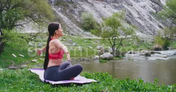 在令人惊叹的自然景观中一位美丽的运动女士在令人惊叹的湖景前的垫子上练习瑜伽冥想视频的预览图