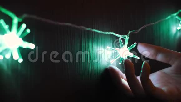 靠近温柔的女人手触摸圣诞花环灯泡的形式绿色的星星概念女性手视频的预览图