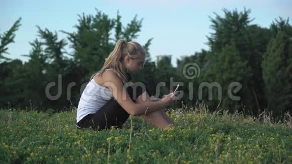 年轻的女孩衬衫坐在山上在你的手机上得到了一条信息视频的预览图