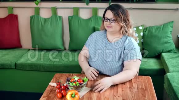 饮食中的积极肥胖妇女在咖啡馆的餐桌上摆着新鲜的有机蔬菜沙拉视频的预览图