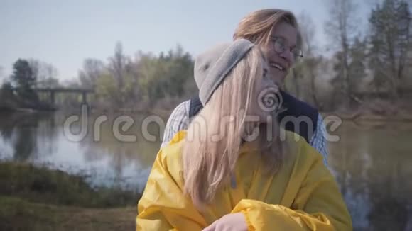 年轻快乐的美丽夫妇拥抱在河和森林的惊人景色附近视频的预览图