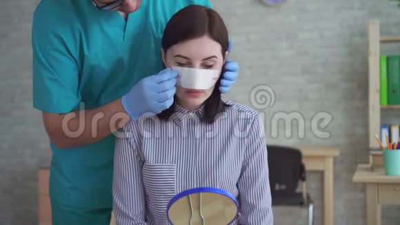 男医生整形外科医生在手术后她的脸上除去绷带视频的预览图