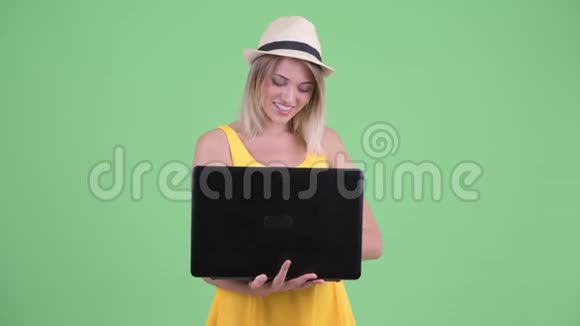 一位年轻的金发碧眼的旅游女伴在用手提电脑说话视频的预览图