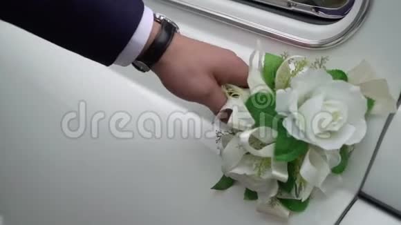 一个男人打开婚礼车的门白色复古车新郎坐在汽车里视频的预览图