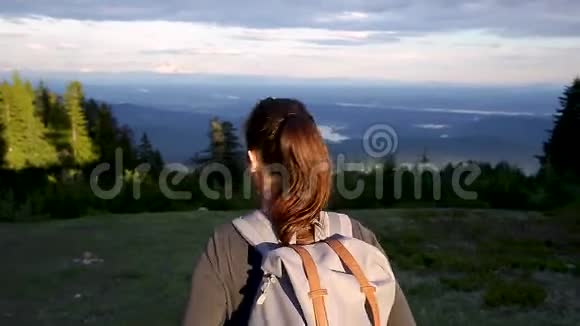 一个年轻的白种人黑发女人背着背包走在森林里的山路上阳光照耀着她视频的预览图