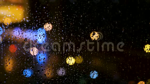 窗后一个大城市的美丽的离焦明亮的灯光和水滴概念雨点落在玻璃上视频的预览图