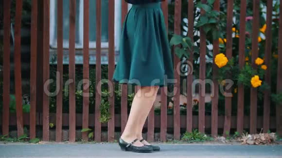 一个年轻漂亮的女人穿着翡翠裙子穿着黑色的鞋子在栅栏边跳舞视频的预览图