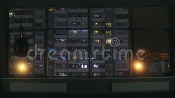 从一个大的空训练馆的窗户到晚上的高住宅楼的视野库存录像城市视频的预览图