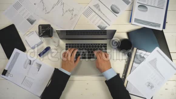 年轻商人的双手在纸上看图表在笔记本电脑键盘上输入文字视频的预览图