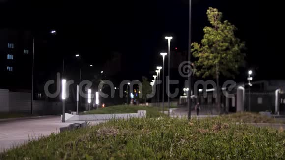 公共公园基础设施及夜间照明库存录像穿过城市公园附近绿色小巷的人视频的预览图