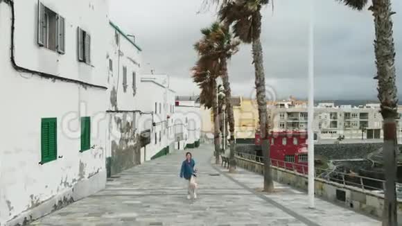 从无人驾驶飞机上看到的景象一名妇女沿着海滨行驶旁边是岛上首府西班牙的老房子视频的预览图