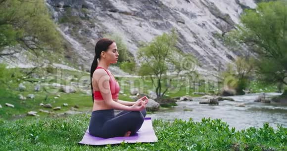 瑜伽使一位年轻的女士在巨大的景观前面的垫子上冥想练习视频的预览图