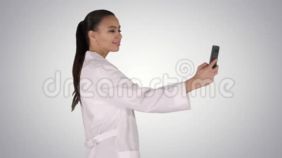 时尚的欧洲医生黑发在电话自拍而走在梯度背景视频的预览图