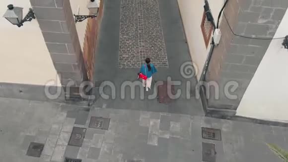 从上往下看一个年轻的女人走在老城的一条狭窄的街道上在首都加那利岛一个视频的预览图