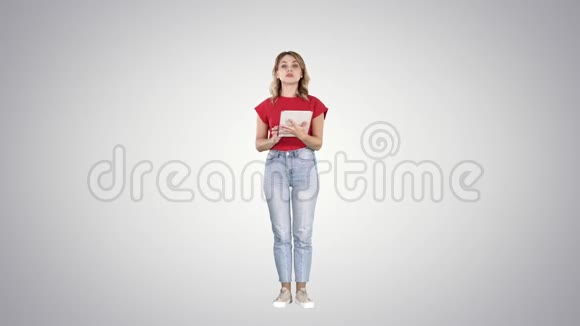 女人在平板电脑上阅读在渐变背景下与相机交谈视频的预览图