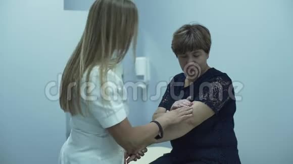 职业白种人医生检查坐在办公室的一名老年妇女的手臂成熟的女士检查她的健康视频的预览图